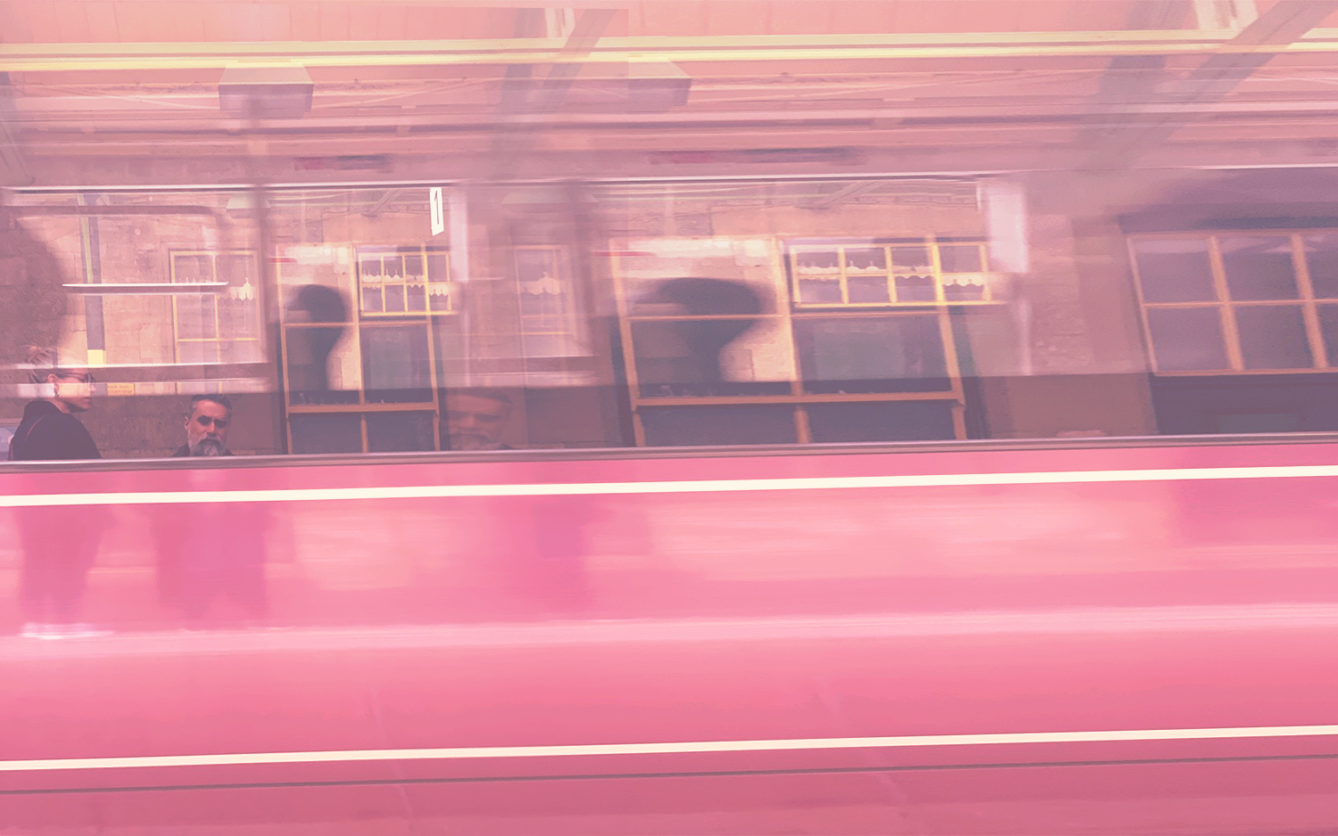 A passing red vehicle with reflected figures and buildings